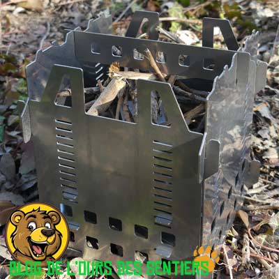 Réchaud à bois pliant Fabogliss avec petit bois et support popote installé pour bivouac.