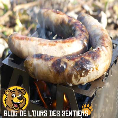 Grille de cuisson réchaud Fabogliss utilisée pour griller saucisses et viande en bivouac.